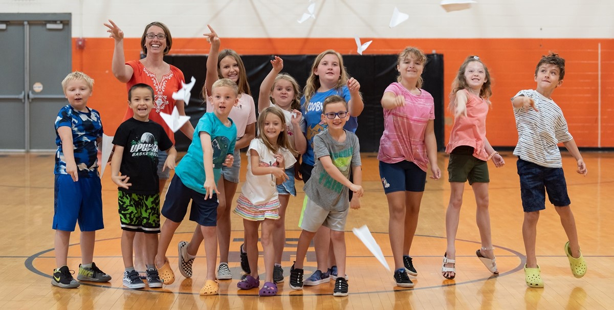 Elementary School Students throwing paper airplanes